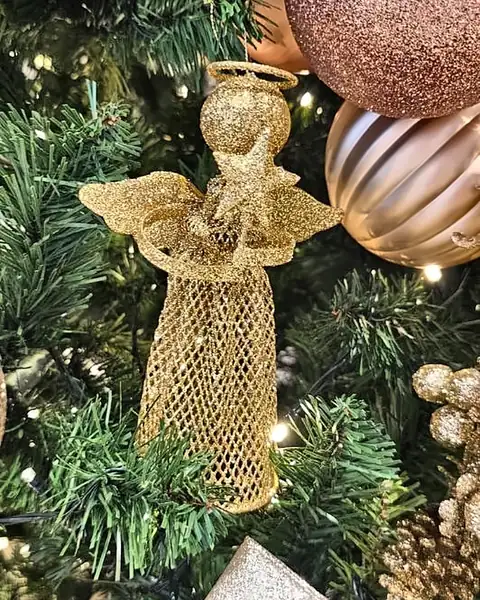 Anjo dourado de tela pendurado entre bolas rosé